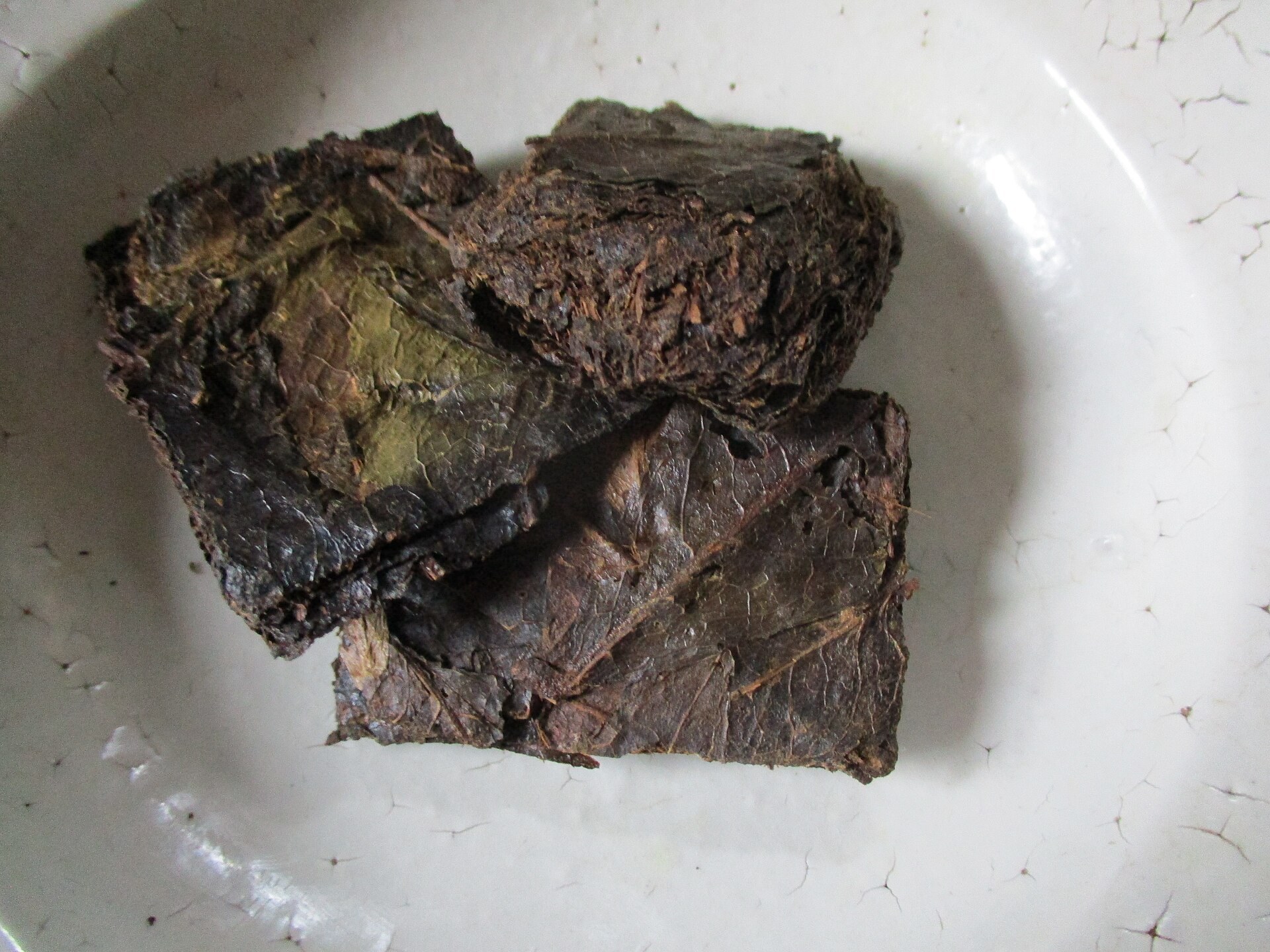 小皿に載せた碁石茶の茶葉。四角い黒い塊がそのまま残っている